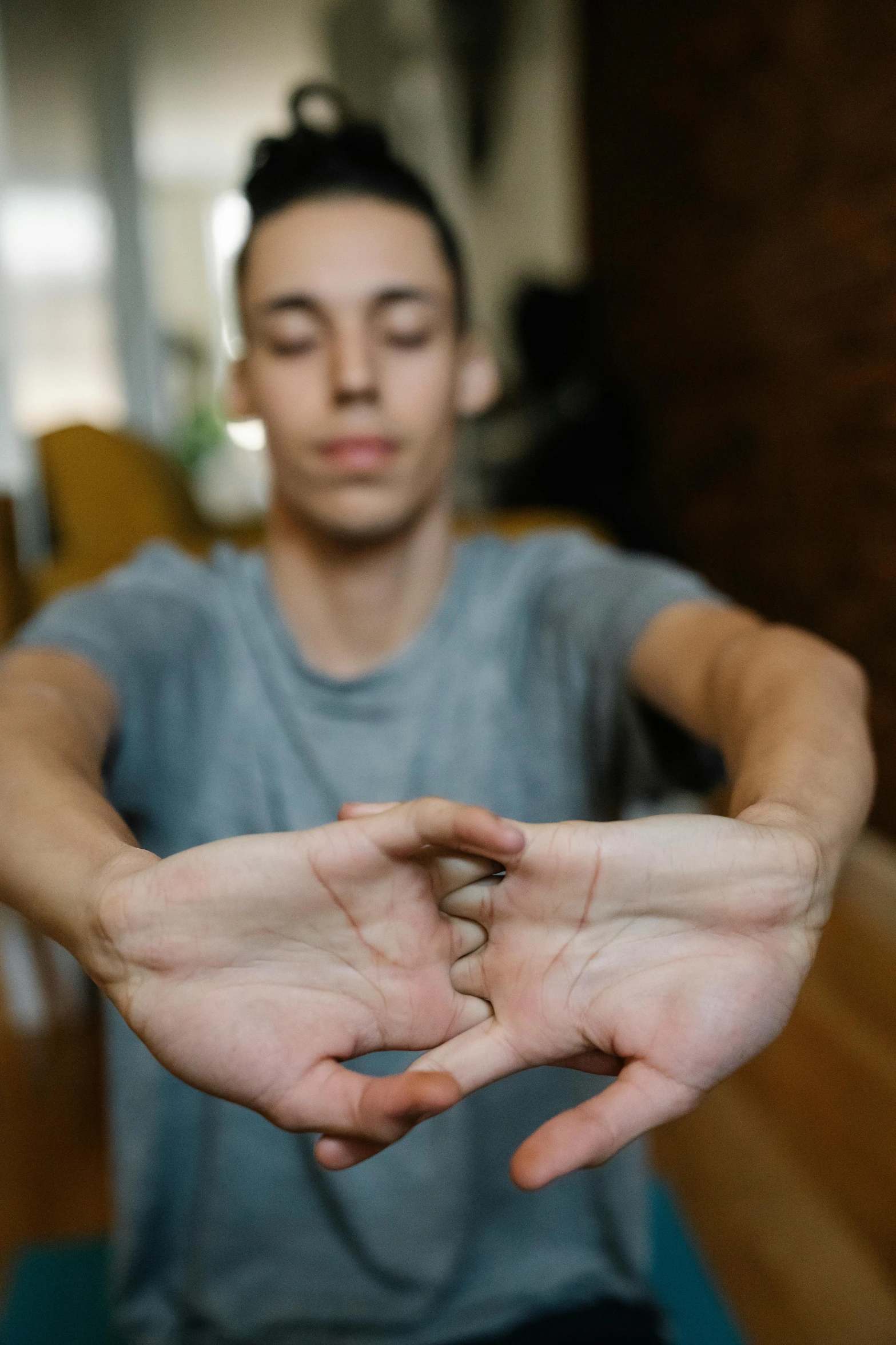 a man sitting on a yoga mat making a heart sign with his hands, by Carey Morris, unsplash, male teenager, centered in portrait, close-up of thin soft hand, three-dimensional