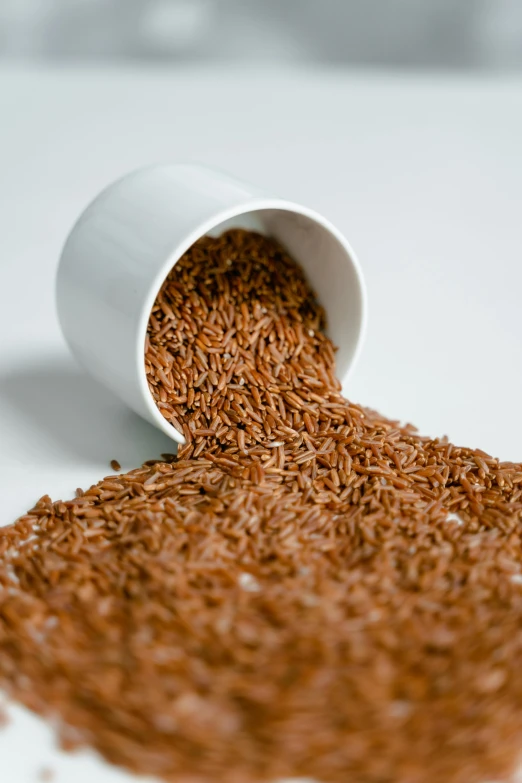 a cup filled with brown rice sitting on top of a table, light scatter, detailed product image, reddish - brown, detail shot