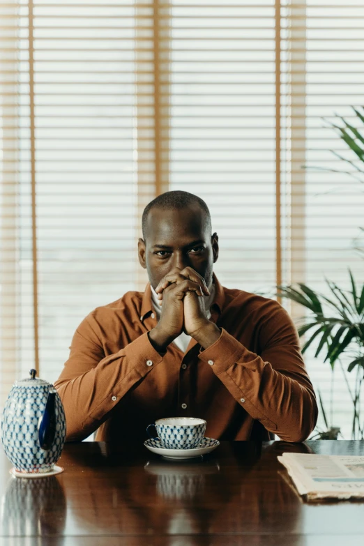 a man sitting at a table with a cup of coffee, kevin garnett, hear no evil, gilleard james, soulful