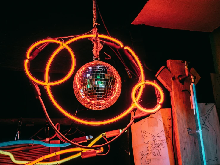 a disco ball hanging from the side of a building, neon basement, red and yellow light, inside a bar, red wires wrap around