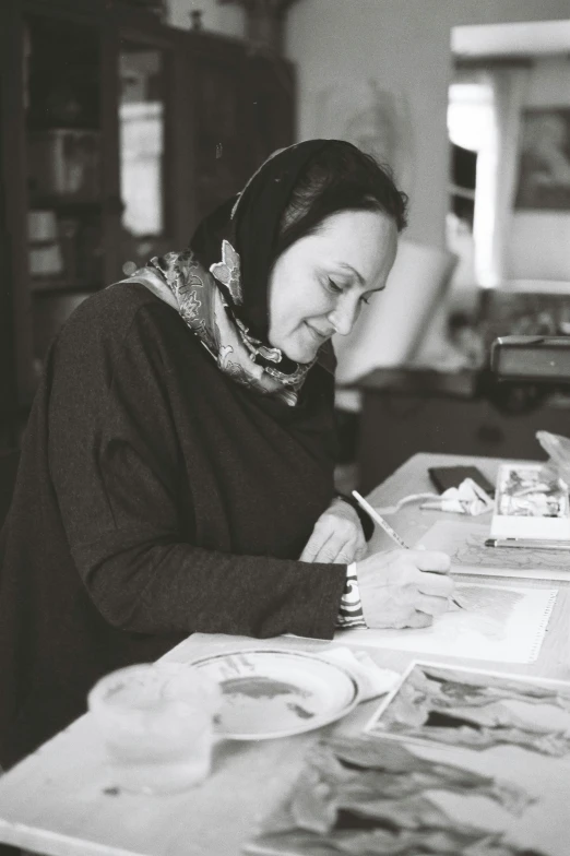 a black and white photo of a woman sitting at a table, a charcoal drawing, pexels, qajar art, in a workshop, shabab alizadeh, promotional image, profile image