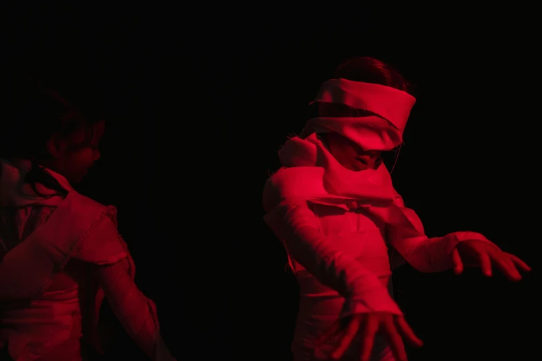 a couple of people that are standing in the dark, by Emma Andijewska, unsplash, video art, red cloth, blindfolded, puppets, abstract human figures dancing
