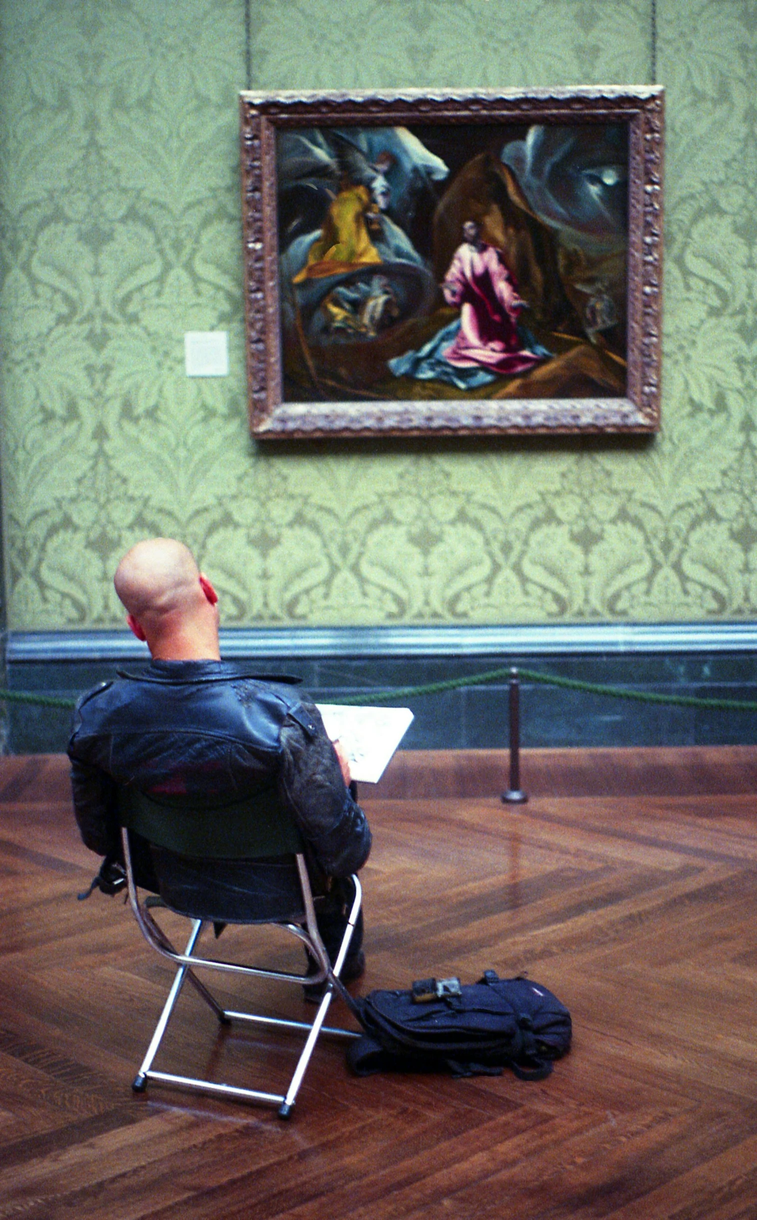 a man sitting in a chair in front of a painting, inspired by Pieter Jansz Saenredam, pexels, louvre, reading, sittin, tourist photo