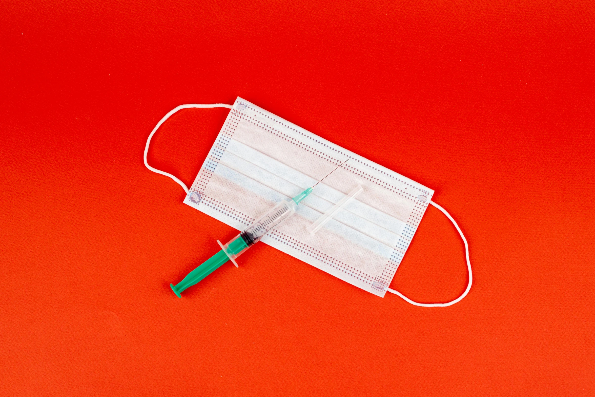 a medical mask and a syssor on a red background, by Adam Marczyński, shutterstock, plasticien, syringe, on white paper, green facemask, rectangle