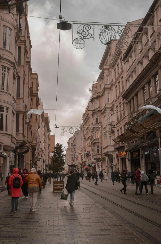 a group of people walking down a street next to tall buildings, by Niyazi Selimoglu, pexels contest winner, art nouveau, ottoman empire, winter, people shopping, nice slight overcast weather