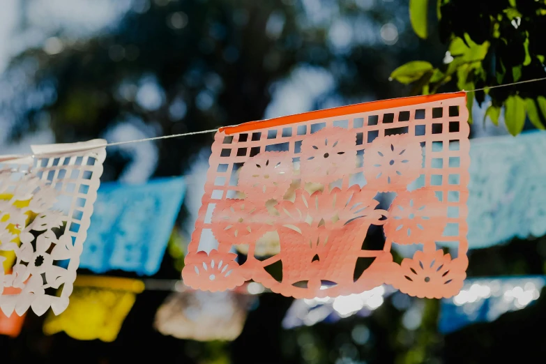 a bunch of paper decorations hanging from a line, by Jessie Algie, pexels contest winner, folk art, orange and turquoise, hispanic, morning sunlight, laser cut