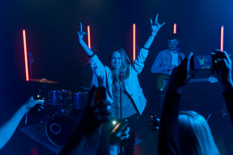 a group of people standing on top of a stage, an album cover, pexels, happening, neon operator margot robbie, ! movie scene, band playing, a still of a happy