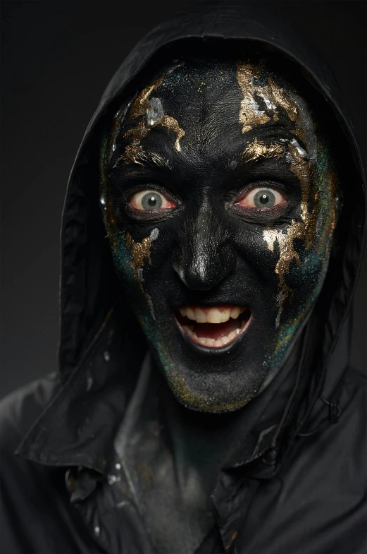 a man with black and gold paint on his face, an album cover, reddit, wearing apocalyptic clothes, 2019 trending photo, looking happy, large black eyes