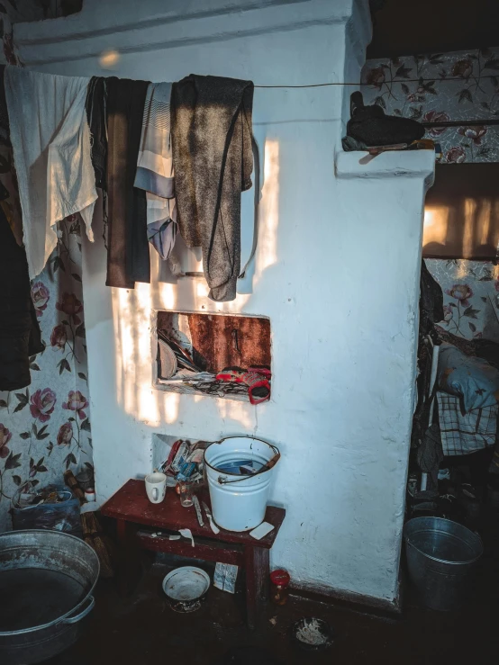 a room with a bunch of clothes hanging on the wall, a portrait, pexels contest winner, socialist realism, inside house in village, inside a tomb, 8k octan photo, light coming from the entrance