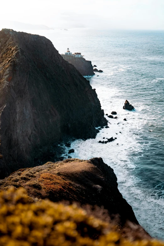 a man standing on top of a cliff next to the ocean, a tilt shift photo, by Kristin Nelson, pexels contest winner, a road leading to the lighthouse, central california, medium format. soft light, panoramic