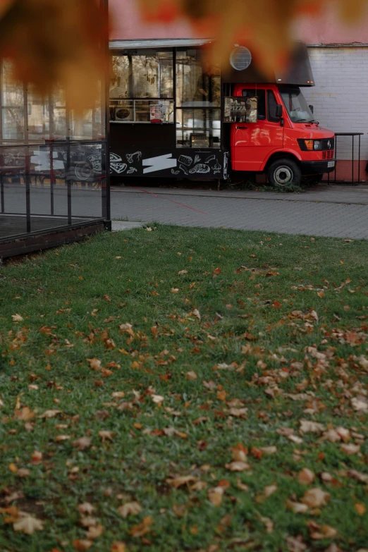 a red fire hydrant sitting on top of a lush green field, an album cover, by Attila Meszlenyi, realism, autumn leaves on the ground, snake van, restaurant in background, cinestill 800t 35mm eastmancolor