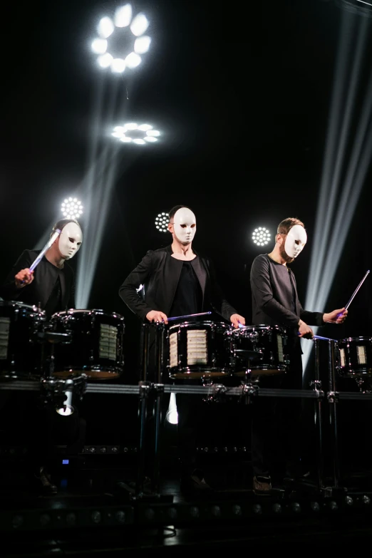 a group of people standing on top of a stage, drum pads, 3 heads, black on black, cybersuits