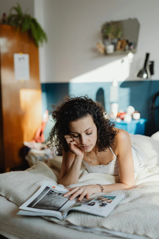 a woman laying in bed reading a magazine, a cartoon, by Julia Pishtar, pexels contest winner, disappointed, curly haired, in the early morning, bright natural light