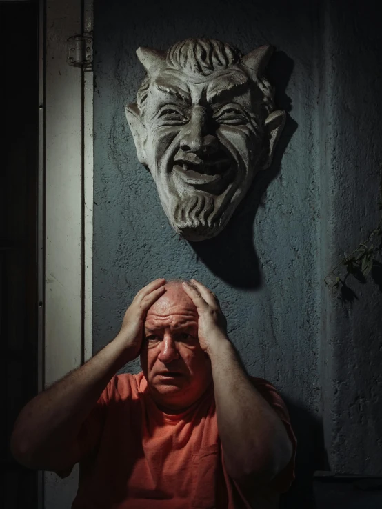 a man holding his head in front of a wall, a statue, pexels contest winner, the devil, wrinkles, ((portrait)), halloween
