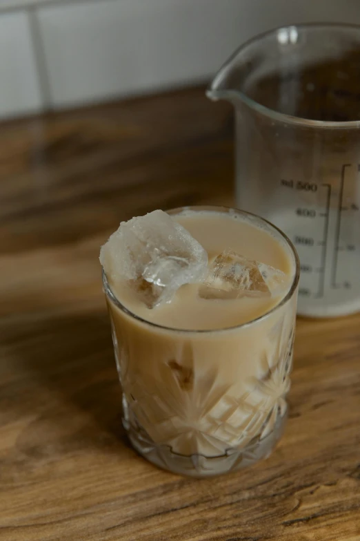 a glass of iced coffee sitting on top of a wooden table, by Jessie Algie, reddit, milk cubes, absinthe, ignant, intense albino