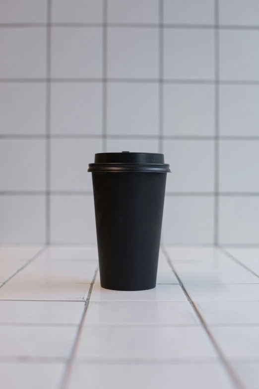 a black coffee cup sitting on top of a white tiled floor, by Harvey Quaytman, reddit, paper cup, thumbnail, large tall, abcdefghijklmnopqrstuvwxyz