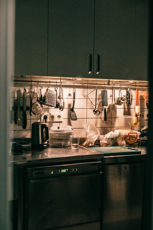 a kitchen with a lot of utensils hanging on the wall, pexels contest winner, night time low light, stainless steal, high quality photo, snacks