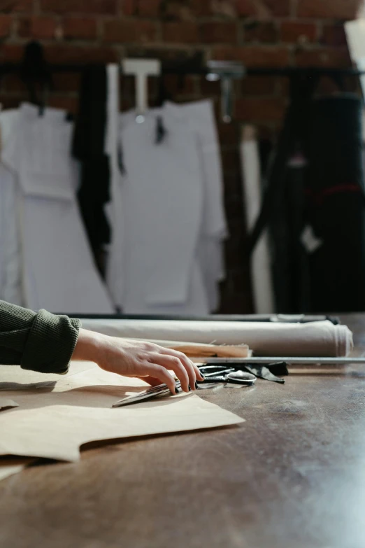 a person sitting at a table working on a piece of paper, tailored clothing, leather robes, white, tools