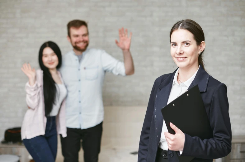 a woman holding a folder standing next to a man, a picture, pexels contest winner, waving, corporate photo, background image, woman holding another woman