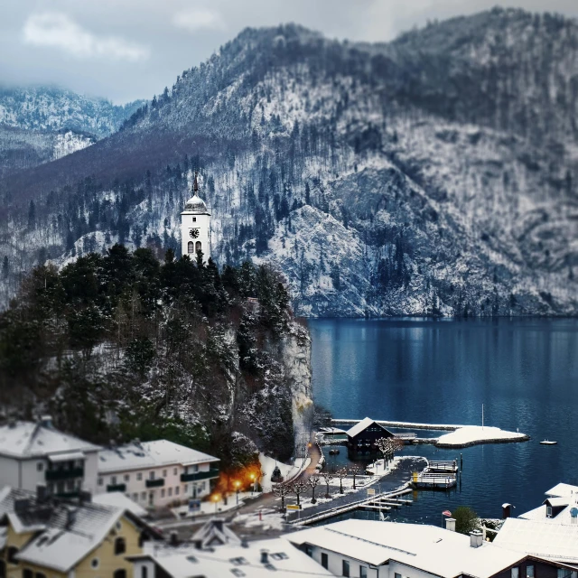 a large body of water surrounded by snow covered mountains, a tilt shift photo, pexels contest winner, renaissance, church in the background, wintry rumpelstiltskin, slovenian, cliffside town