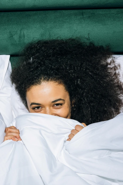 a close up of a person laying in a bed, trending on pexels, black curly hair, cloak covering face, all overly excited, beds