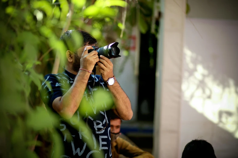 a man taking a picture with a camera, by Riza Abbasi, pexels contest winner, photorealism, shady look, environment, action shot, event photography