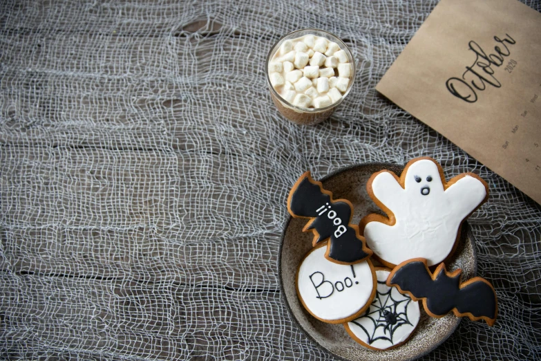 a plate that has some cookies and marshmallows on it, by Emma Andijewska, pexels, graffiti, halloween wallpaper with ghosts, background image, white table, ginger