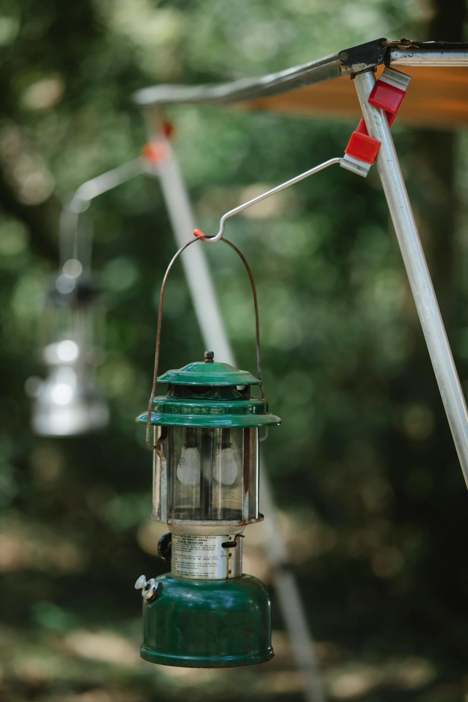 a green lantern hanging from a metal pole, unsplash, visual art, glamping, holding electricity and birds, lamps, hummingbirds