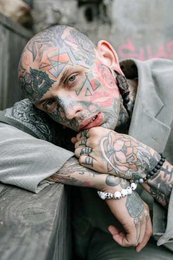 a man with tattoos sitting on a bench, a tattoo, inspired by Seb McKinnon, trending on pexels, hyperrealism, clear sharp todd solondz face, arms covered in gang tattoo, gangster, large)}]