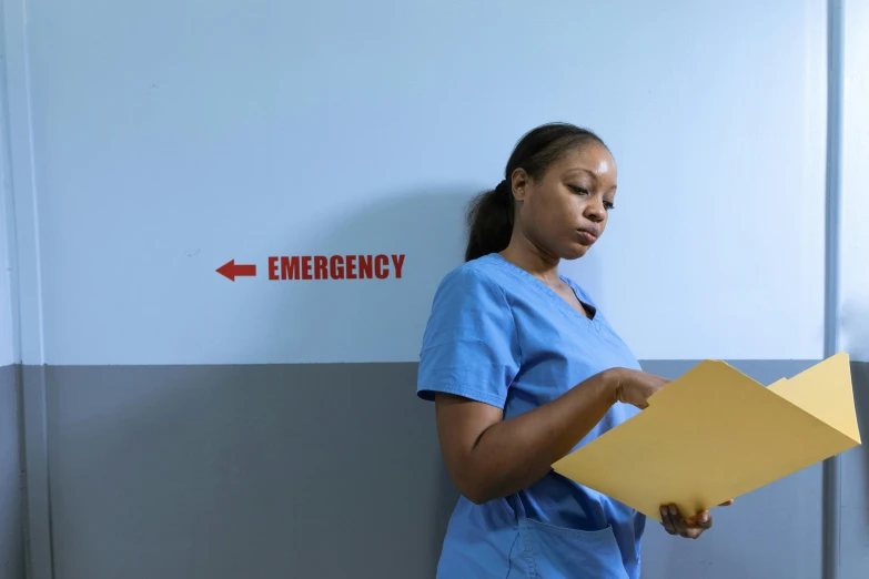 a woman in a blue scrub suit holding a folder, pexels, happening, emergency room, photo of a black woman, 15081959 21121991 01012000 4k, still image from tv series