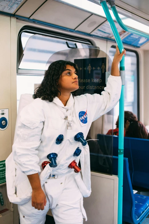 a woman in a space suit on a subway train, by Helen Stevenson, trending on unsplash, imaan hammam, wearing lab coat, moon landing, holding a wand