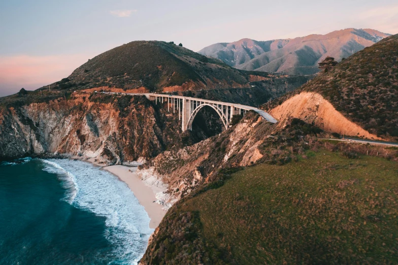 a bridge over a body of water with mountains in the background, by Carey Morris, pexels contest winner, renaissance, coastal cliffs, it's californication, 2 5 6 x 2 5 6 pixels, unsplash 4k