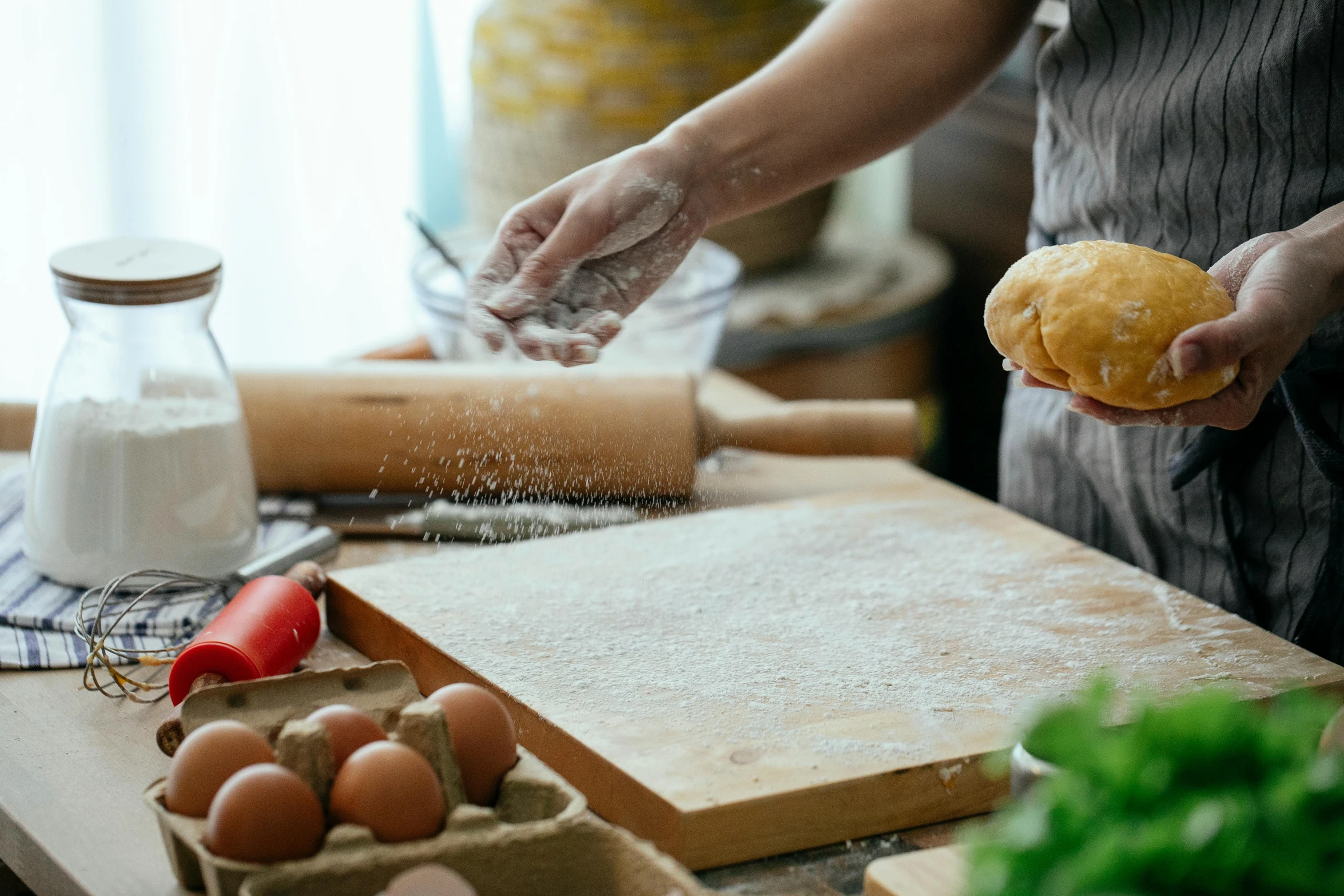 a woman is sprinkling flour on a doughnut, a still life, trending on pexels, cooking pizza, leather apron, thumbnail, a wooden