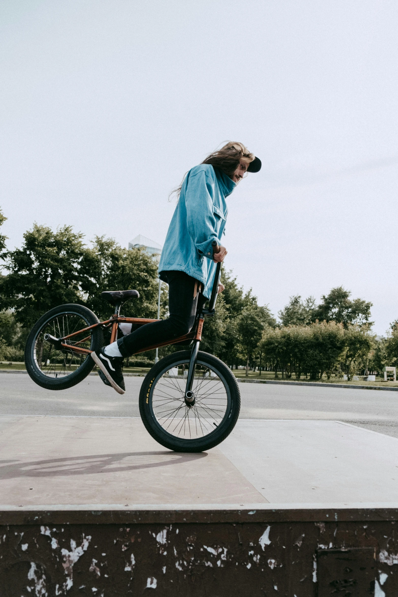 a man riding a bike up the side of a ramp, pexels contest winner, woman in streetwear, plain background, park in background, lifted