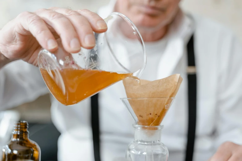 a close up of a person pouring something into a glass, inspired by Richmond Barthé, renaissance, parchment paper, mad scientist working, caramel, thumbnail