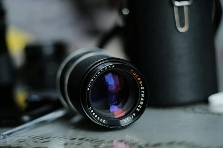 a close up of a camera lens on a table, by Niels Lergaard, unsplash, photorealism, hasselblad film bokeh, vintage colours, carl zeiss, aperture f/9