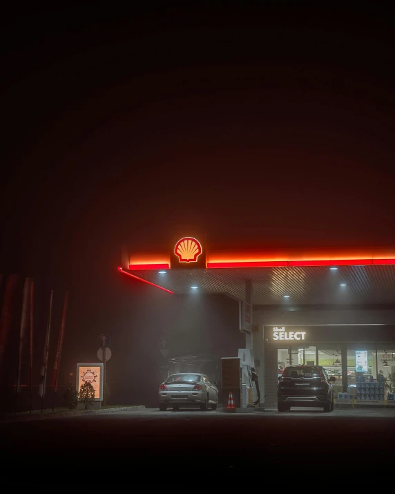 a gas station at night with cars parked in front of it, inspired by Elsa Bleda, pexels contest winner, australian tonalism, foggy day outside, shell, red and white neon, cold mist black background