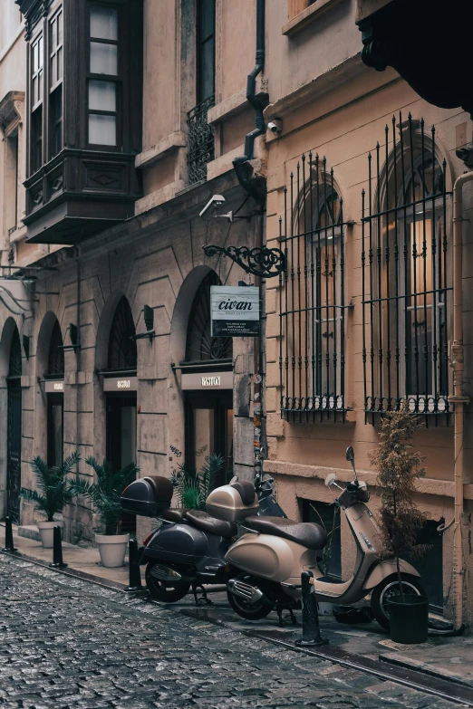 a scooter is parked on a cobblestone street, by Riad Beyrouti, pexels contest winner, art nouveau, full building, gif, talaat harb square cairo, exterior view