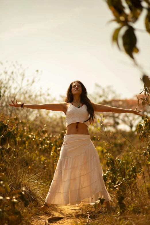 a woman standing in a field with her arms outstretched, unsplash, renaissance, white skirt and barechest, anjali mudra, sun lighting, in a jungle environment
