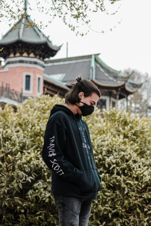 a man standing on a skateboard in front of a building, an album cover, by Nina Hamnett, trending on unsplash, graffiti, dressed black hoodie, traditional chinese clothing, one single mask, wearing sweatshirt