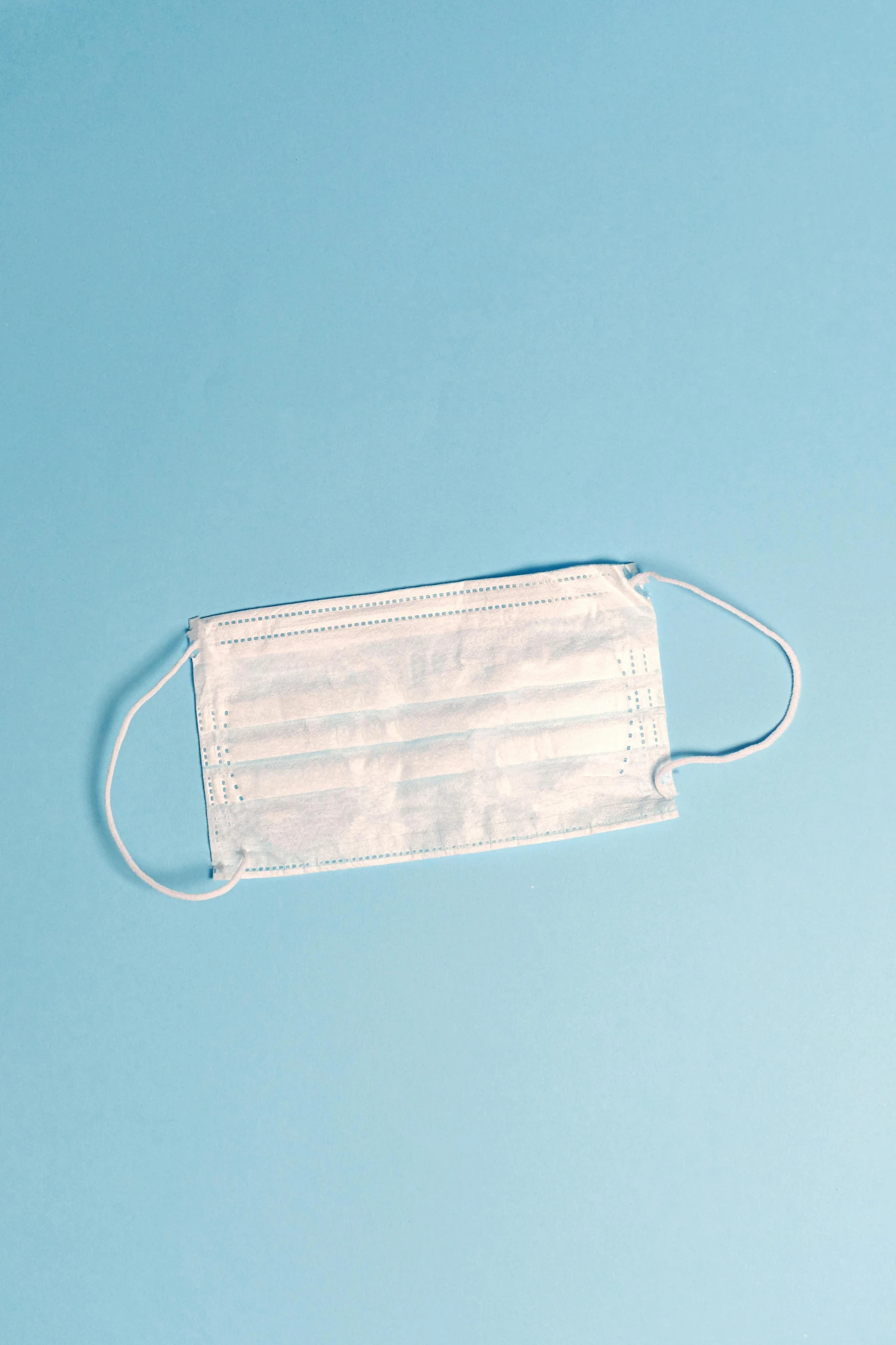 a white face mask on a blue background, surgical iv bag, thumbnail, high - angle view, medium