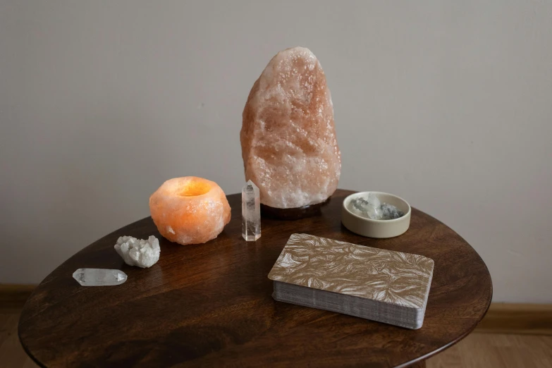 a table that has some rocks and a candle on it, a marble sculpture, by Jessie Algie, himalayan rocksalt lamp, light source from the left, studio shot, light orange mist