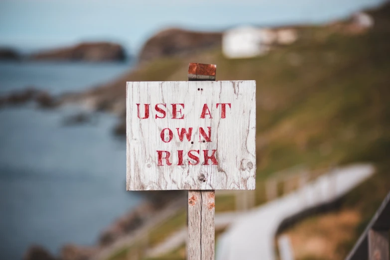 a close up of a sign near a body of water, unsplash, excessivism, steep cliffs, avatar image, brown, osr