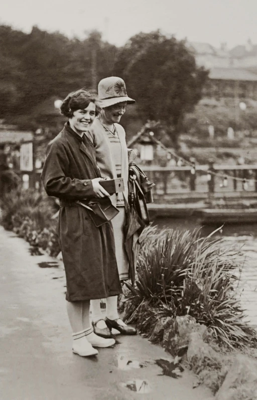 a couple of women standing next to a body of water, inspired by Bert Hardy, a still of a happy, gardening, digital image, gentleman