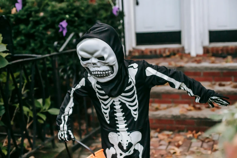 a little boy dressed up in a skeleton costume, by Helen Stevenson, pexels, beistle halloween decor, instagram post, with detailed, trick or treat