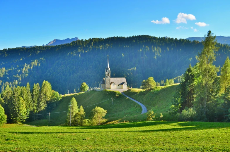 a church sitting on top of a lush green hillside, by Franz Hegi, pexels contest winner, fan favorite, panorama, avatar image, sunny morning light