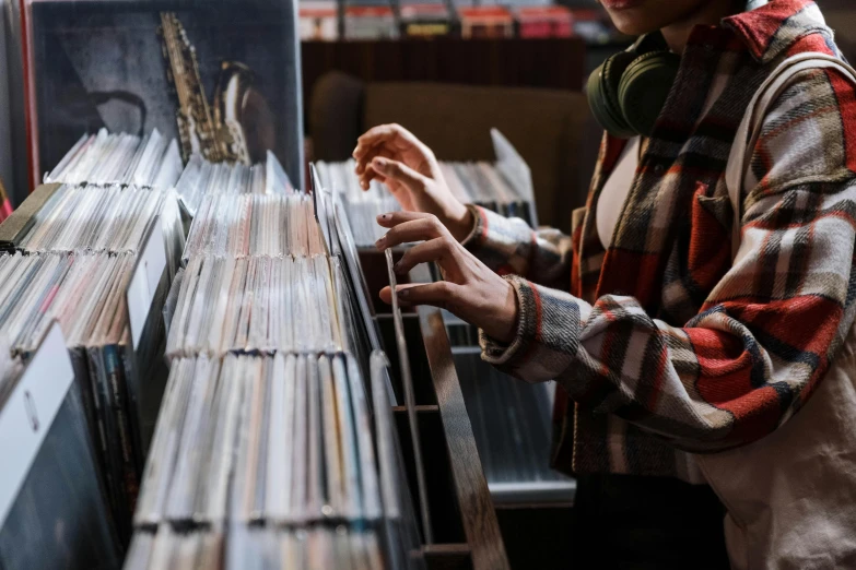 a man standing in front of a rack of records, trending on pexels, rebecca sugar, plays music, australian, inspect in inventory image