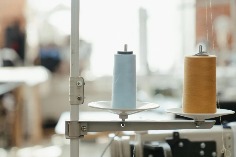 two spools of thread sitting on top of a table, unsplash, private press, tall factory, lead - covered spire, grey, iv pole