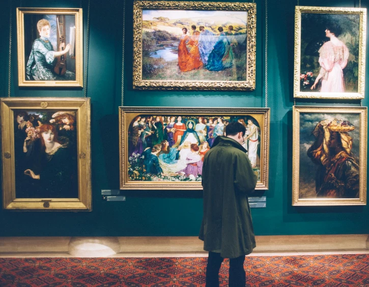 a man standing in front of a wall of paintings, a fine art painting, by Julia Pishtar, pexels contest winner, pre-raphaelitism, people look into the frame, thomas kindkade, fine art print