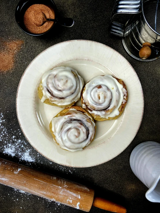 a white plate topped with cinnamon rolls next to a rolling pin, by Winona Nelson, instagram story, high lights, 5k, lemon